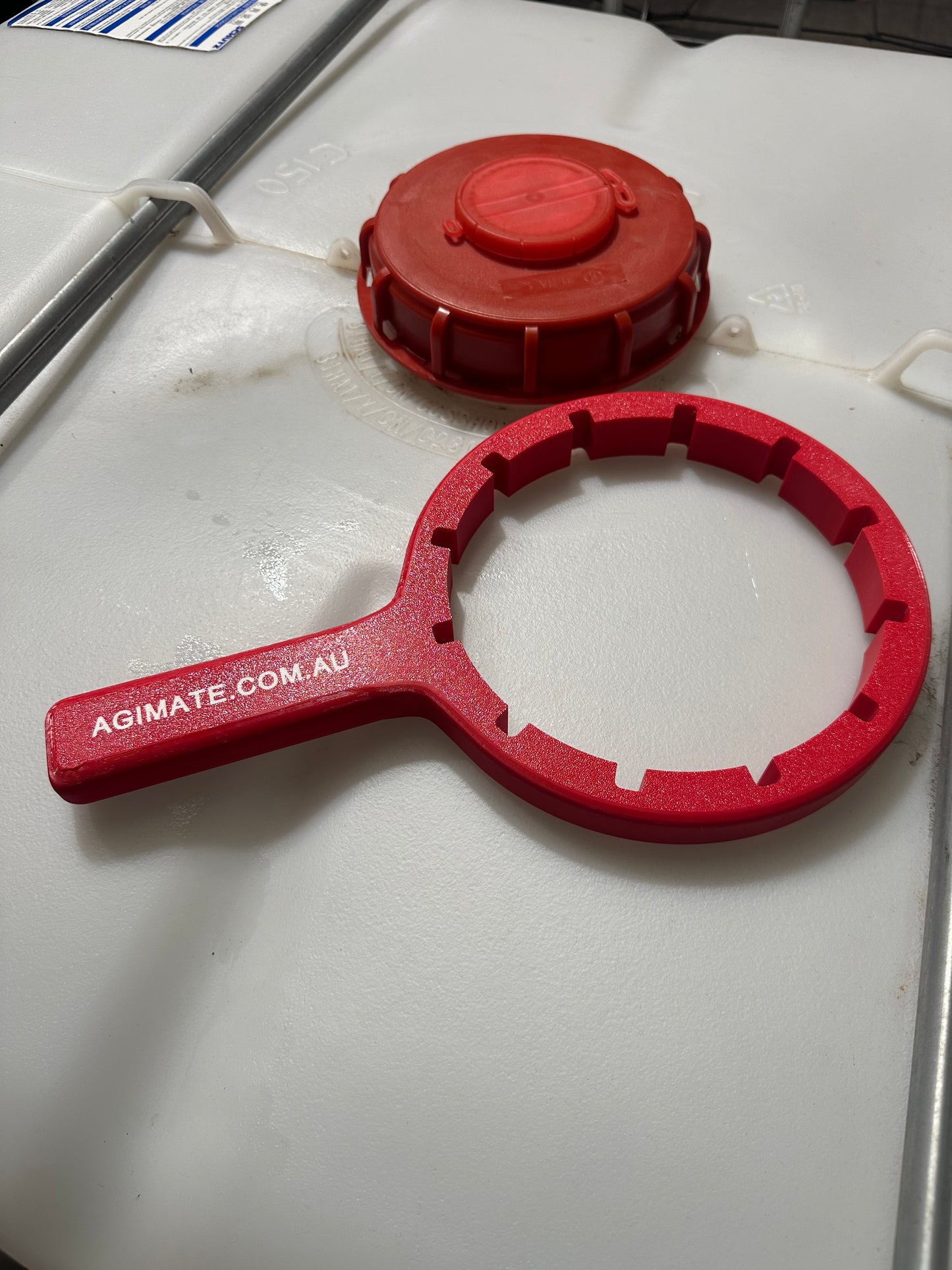 Agimate IBC lid cap spanner beside an open IBC tote cap, showing the notches that grip the cap.