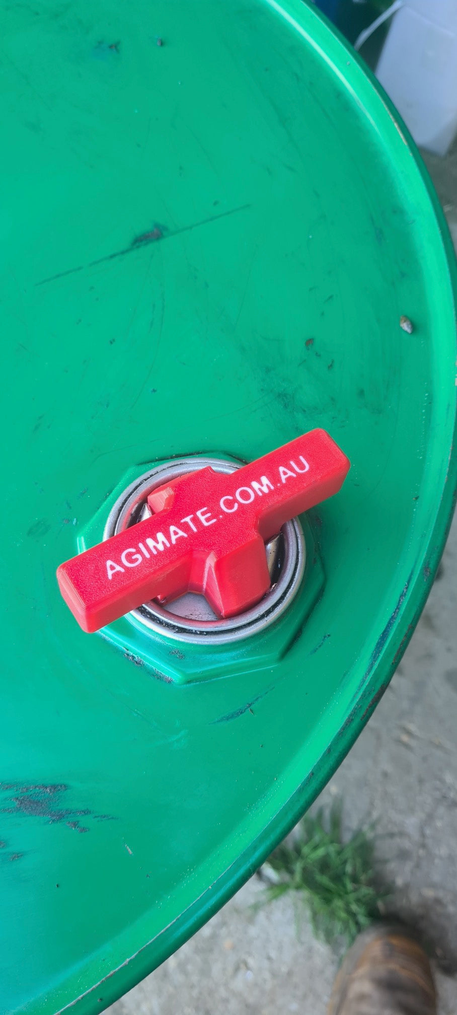 Agimate drum bung key opener fitted into the bung of a green steel drum.