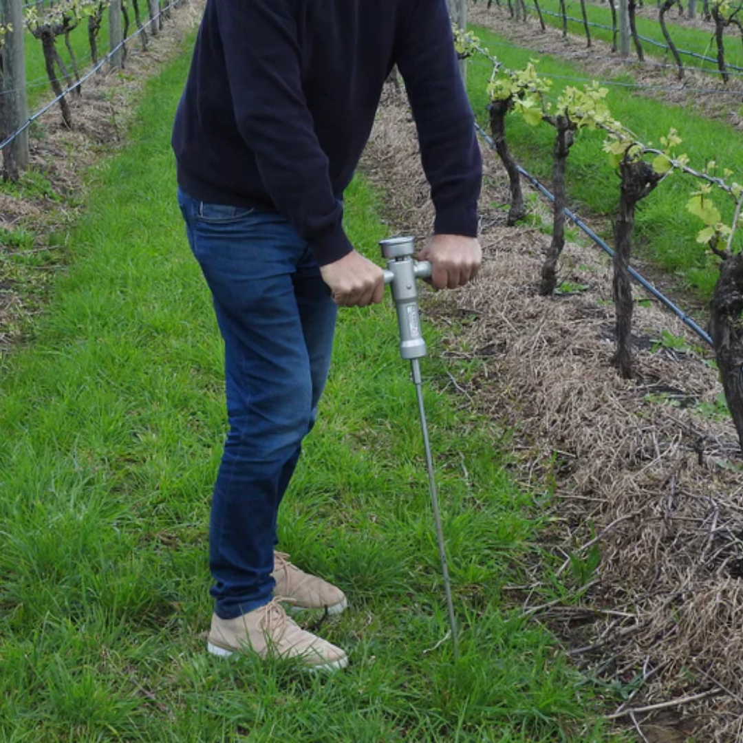 Soil penetrometer probe inserted into soil measuring compaction levels at different depths for agricultural soil analysis